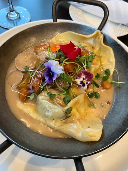 House-made ravioli in a creamy mushroom sauce, garnished with edible flowers, microgreens, and fresh herbs at Dulivia Ristorante Italiano in Springdale, Utah.