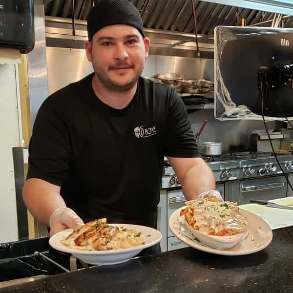 John, Kitchen Manager in the Expo window with 2 plates of food.