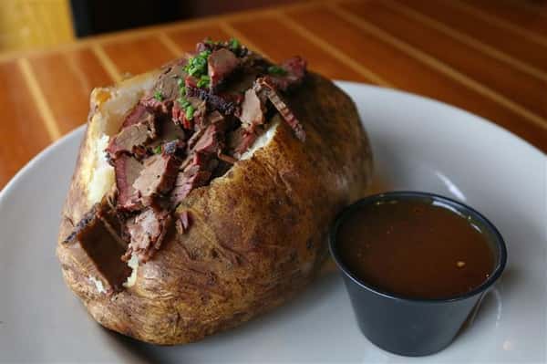 Brisket Potato - Jumbo potato stuffed with cheddar cheese, sour cream & fresh chives then topped with our house smoked Certified Angus Beef(r) brisket & house-made BBQ sauce
