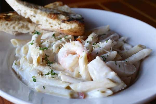 Seafood Alfredo - Shrimp, scallops & snow crab meat with cherry tomatoes over penne pasta in our house-made alfredo sauce