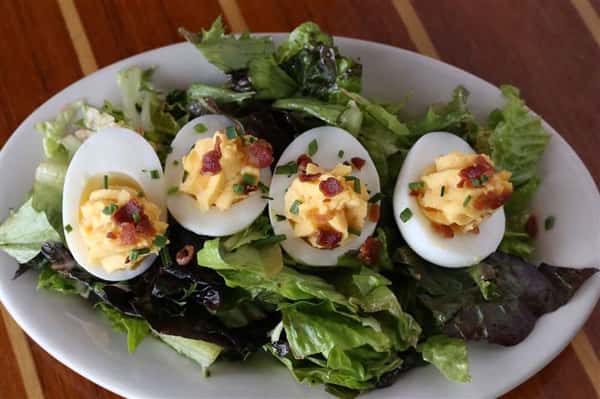 Pimento'd Deviled Eggs - Topped with bacon crumbles & fresh chives served over a small bed of mixed greens tossed in a blood orange vinaigrette