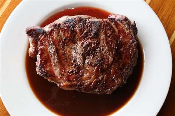 steak on a plate sitting in steak juice.