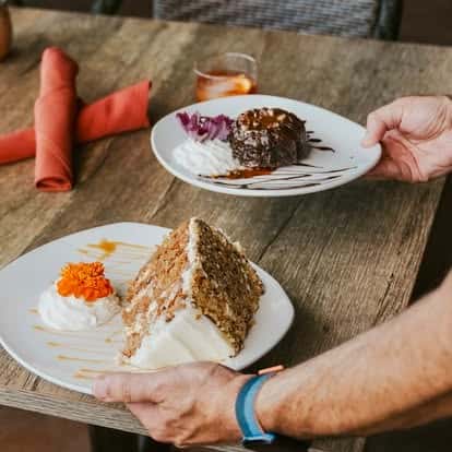 Hand serving a plate of dessert alongside another dish