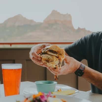 Hand holding a taco outdoors with red rock mountains in the background