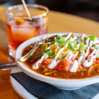 Bowl of enchiladas in red sauce topped with sour cream and cilantro