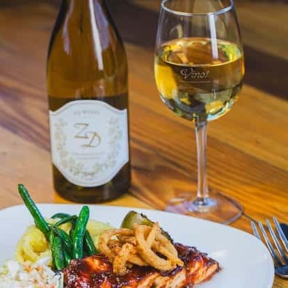 Glass of white wine served with a plate of grilled asparagus