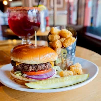 Burger served with tater tots and a red cocktail