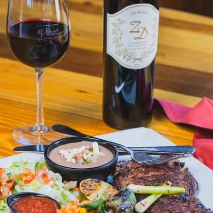 Wine bottle and glass served with a charcuterie and appetizer spread