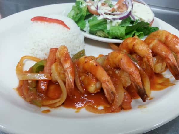 Shrimp lined up on a white plate with scoop of rice