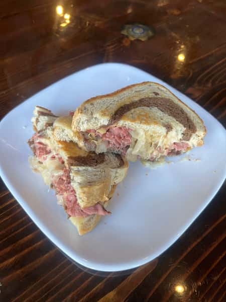 Reuben burger on toasted marbled rye with melted Swiss cheese and stacked corned beef, cut in half
