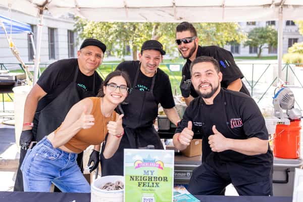 Restaurant team posing at a community food event, celebrating local hospitality, chef-driven cuisine, and neighborhood engagement.