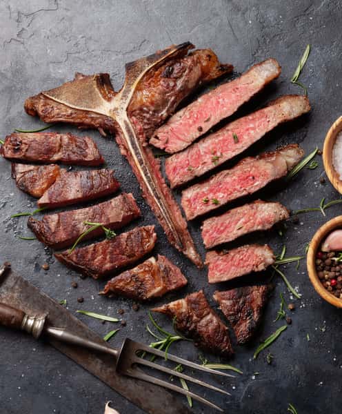 Perfectly grilled tomahawk steak sliced medium-rare and garnished with fresh rosemary, showcasing premium steakhouse cuisine.