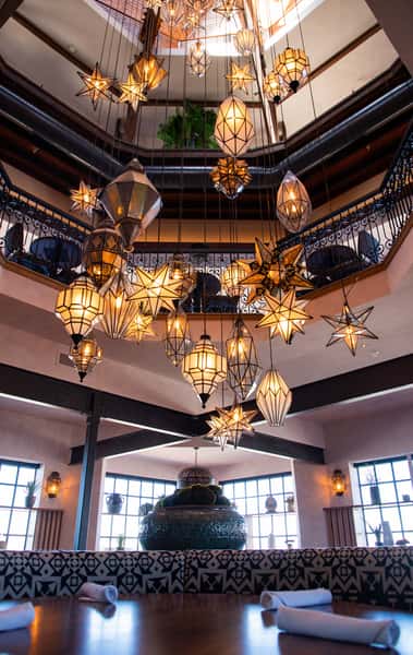 Grand restaurant interior with dramatic star-shaped pendant lighting, elegant balcony seating, and sophisticated architectural design.