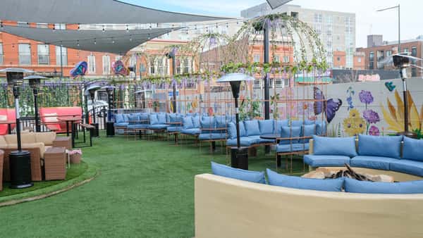 Spacious outdoor patio lounge with cushioned seating, garden-inspired décor, and a relaxed atmosphere for dining and social gatherings.