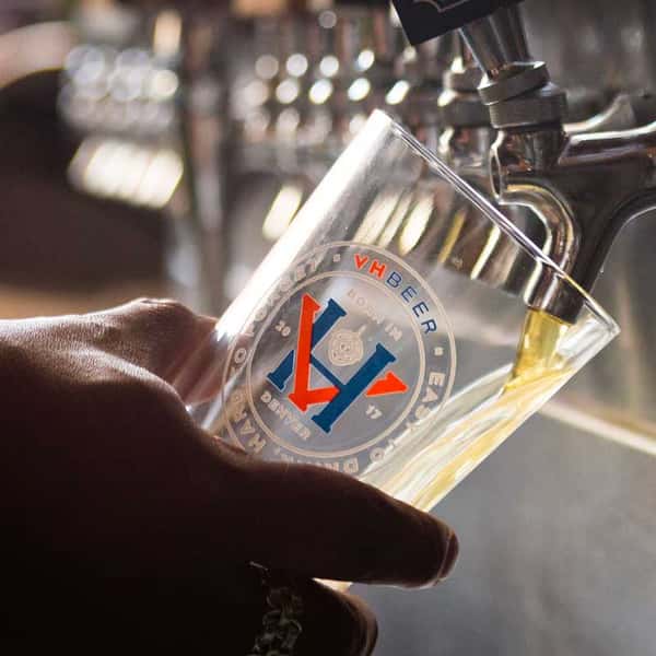 Fresh craft beer being poured from a tap into a branded pint glass, highlighting the brewery's locally brewed beer selection.