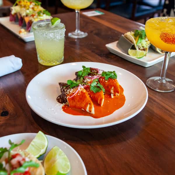 Mexican-inspired entrée served with rich red sauce, fresh cilantro, and handcrafted margaritas on a vibrant restaurant dining table.