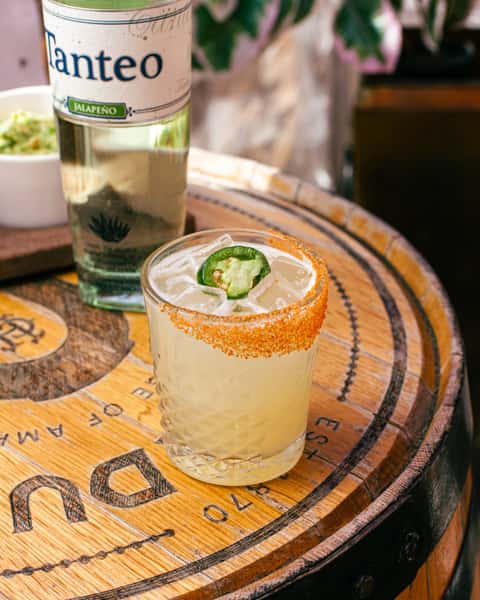 Spicy jalapeño margarita with a chili-salt rim, served over ice alongside premium tequila for a bold cocktail experience.
