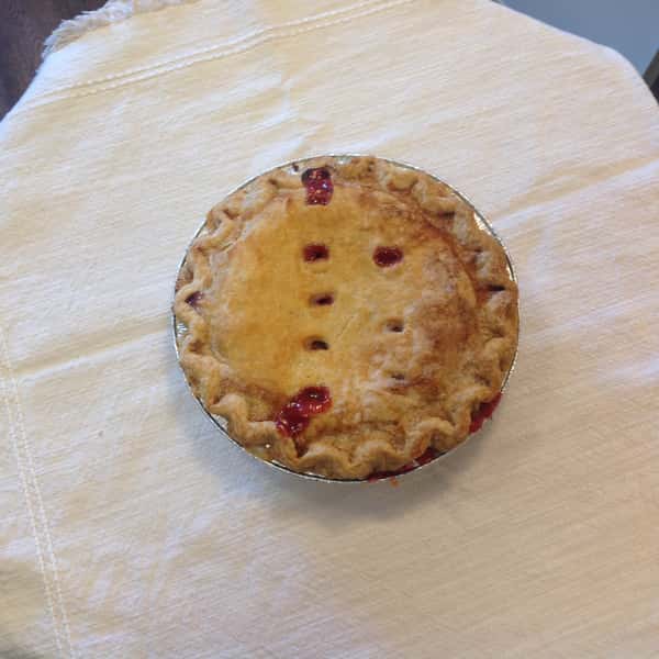 Golden cherry pie from The Sunflower Bakery Café on white cloth.