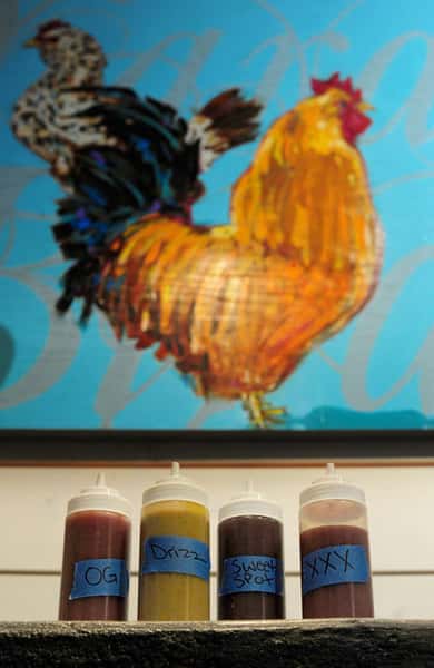 four varieties of sauces in front of rooster mural