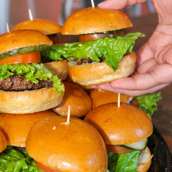 Platter of classic Social Burger slider burgers with fresh lettuce, tomato, pickles, and beef patties, perfect for catering, parties, and group events.