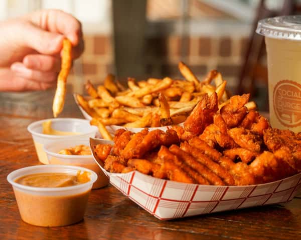 Crispy chicken bites and golden French fries served with signature dipping sauces and a refreshing drink at Social Burger.