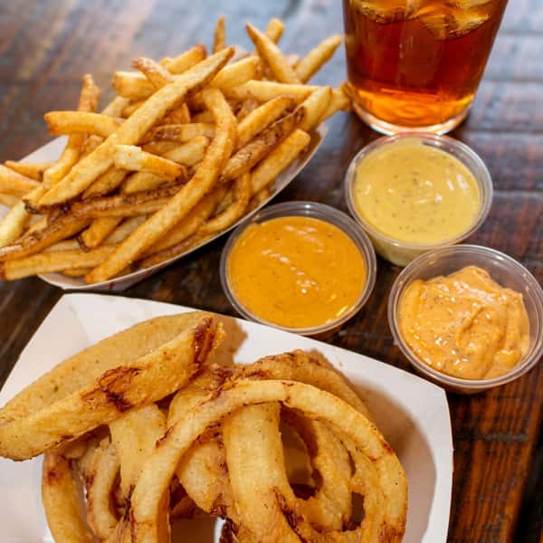 Crispy French fries and golden onion rings served with signature dipping sauces and a refreshing iced drink at Social Burger.