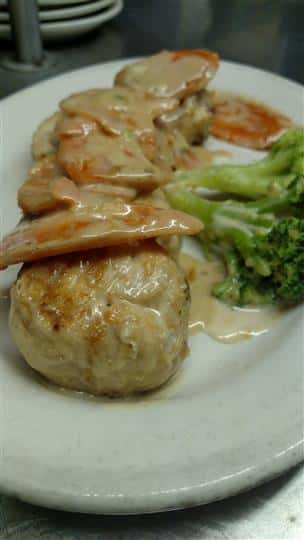 Seafood entree covered in sauce and a side of broccolil