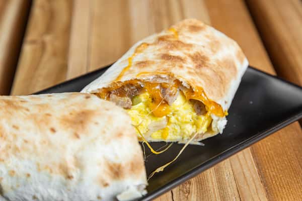 Breakfast wrap filled with eggs, cheese, and sausage cut in half on a black plate at Wisco Coffee Company