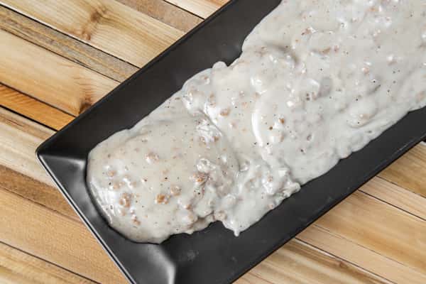 Biscuits smothered in creamy sausage gravy served on a black plate at Wisco Coffee Company