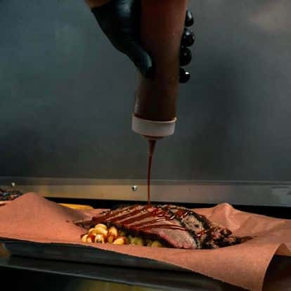 chef pouring sauce over brisket