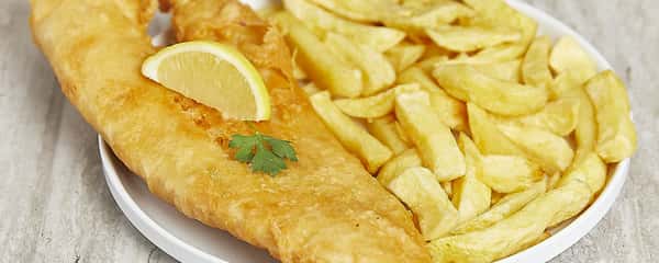 Close-up of fish and chips with lemon wedge and crispy fries.
