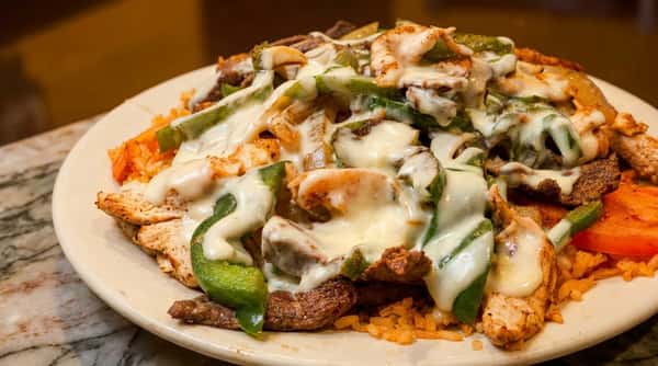Grilled chicken and steak fajitas topped with melted cheese and sautéed peppers at Maya Mexican Restaurant in Alabama.