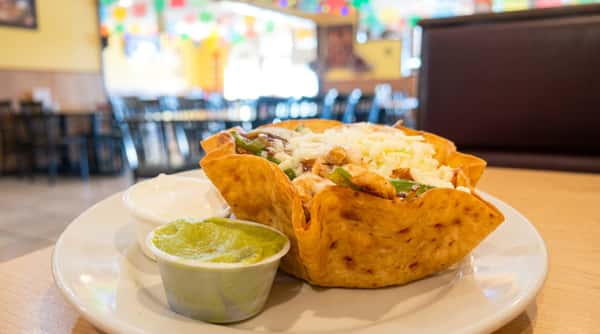 Crispy taco salad filled with seasoned beef, fresh lettuce, tomatoes, shredded cheese, and guacamole at Maya Mexican Restaurant in Homewood and Alabaster, Alabama.