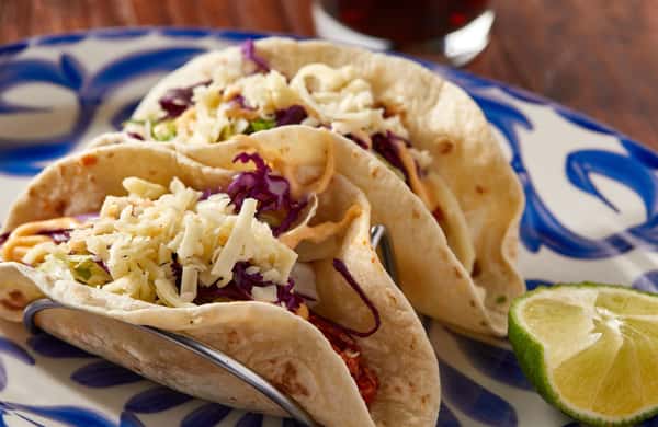 two soft tacos with meat, cabbage, shredded cheese and chipotle mayo.