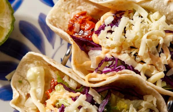 two soft tacos with meat, cabbage, shredded cheese and chipotle mayo.