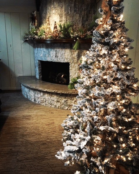 decorated Christmas tree next to stone fireplace