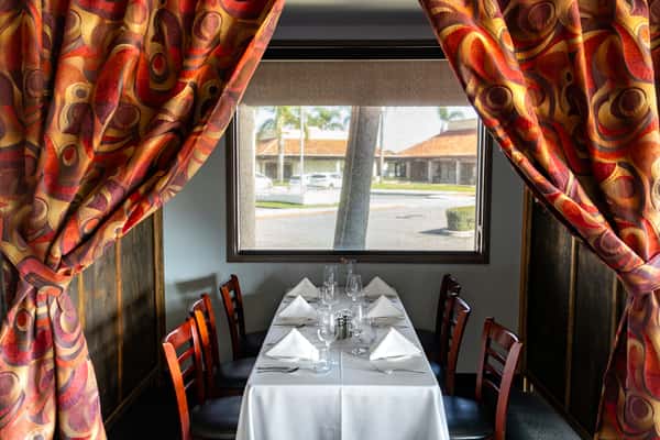 The warm ambiance of 17th Street Grill in Tustin, CA, captured through its intimate table arrangements and ornate wine display, a prime spot for private celebrations.