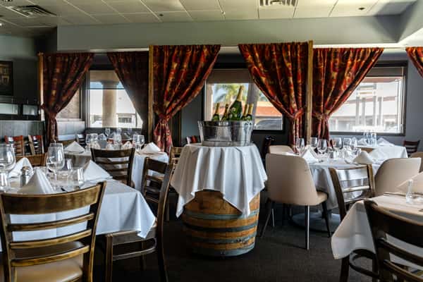 Private event space with floral drapery and wood barrel bar height tables.