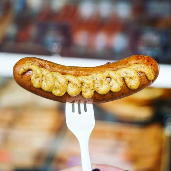 grilled sausage on a fork with blurred restaurant background
