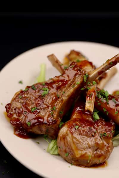 grilled lamb chops with glaze and herbs plated with elegant presentation