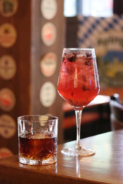 bright red cocktail in stemmed glass on bar with blurred background
