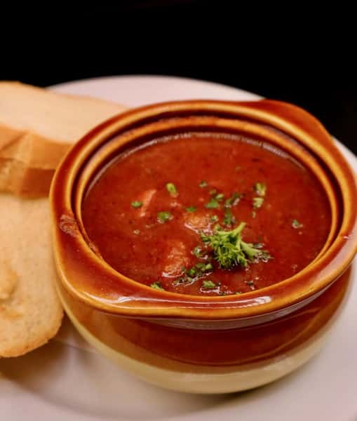 rich tomato soup garnished with herbs in a rustic bowl, comforting starter