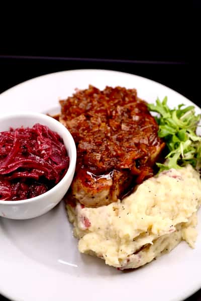 hearty German plate with braised meat, red cabbage, and mashed potatoes