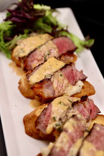 sliced steak sandwich with melted cheese on toasted bread