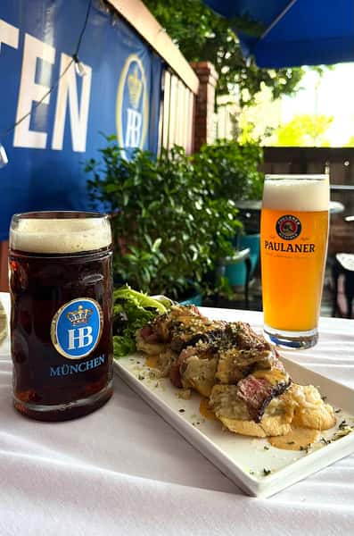 German beer served with grilled meats and herbs on an outdoor table