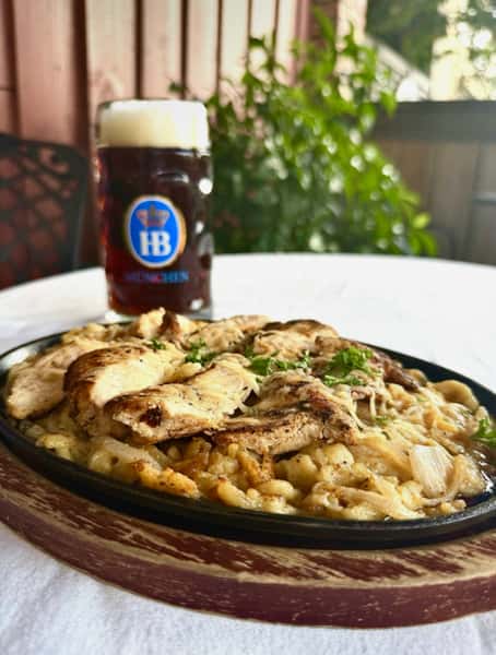 creamy pasta with grilled chicken and herbs served with German beer on table