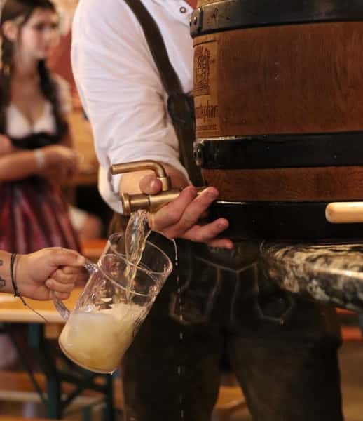 bartender pouring draft beer into a glass from tap behind the bar