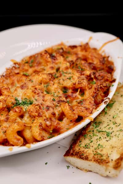 baked cheesy pasta or spaetzle dish with herbs in a white serving dish