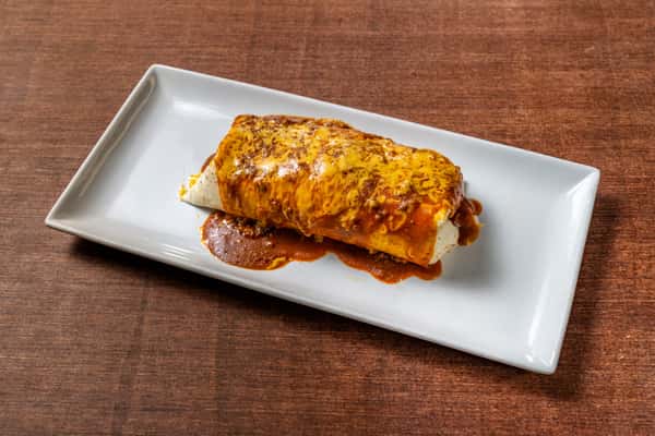 Hearty beef burrito topped with rich red enchilada sauce and melted cheddar cheese, served on a modern rectangular white plate.