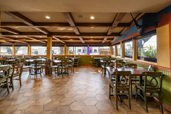 Spacious indoor dining area with rustic wooden beams, cozy booth seating, and large Bright windows filled with natural light—ideal for family meals in a relaxed atmosphere.